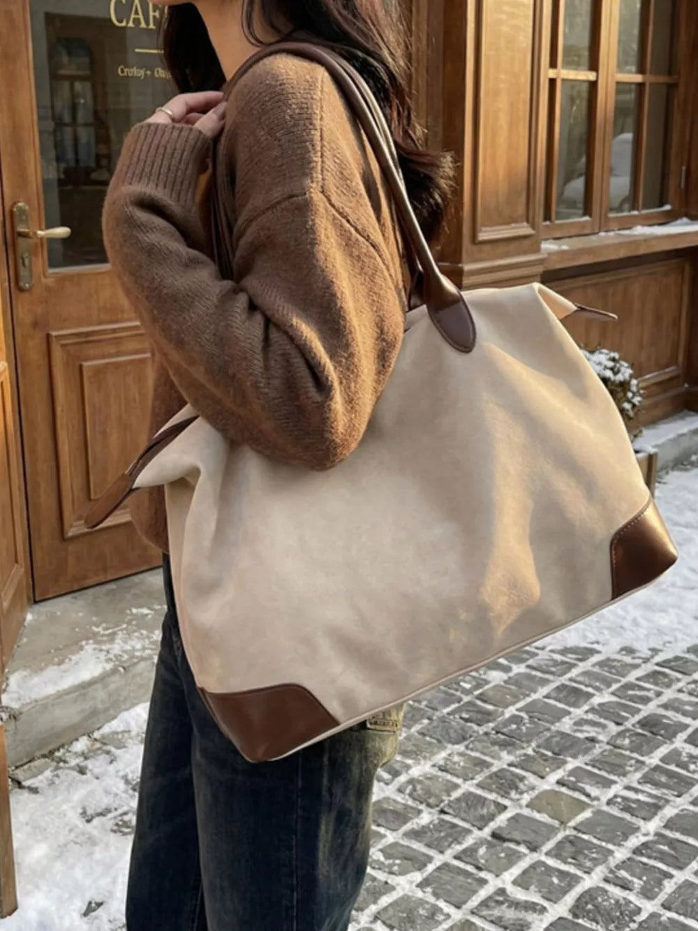 Chic beige slouchy travel bag with camel leather accents and top handles.