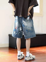 Men's distressed blue denim shorts with paint splatter and graphic print details.