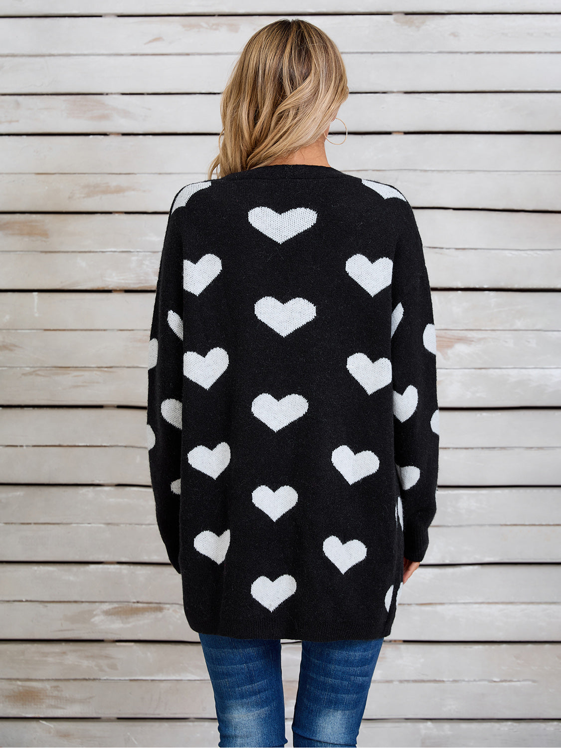 Black acrylic cardigan with white intarsia hearts, crew neck, long sleeves.