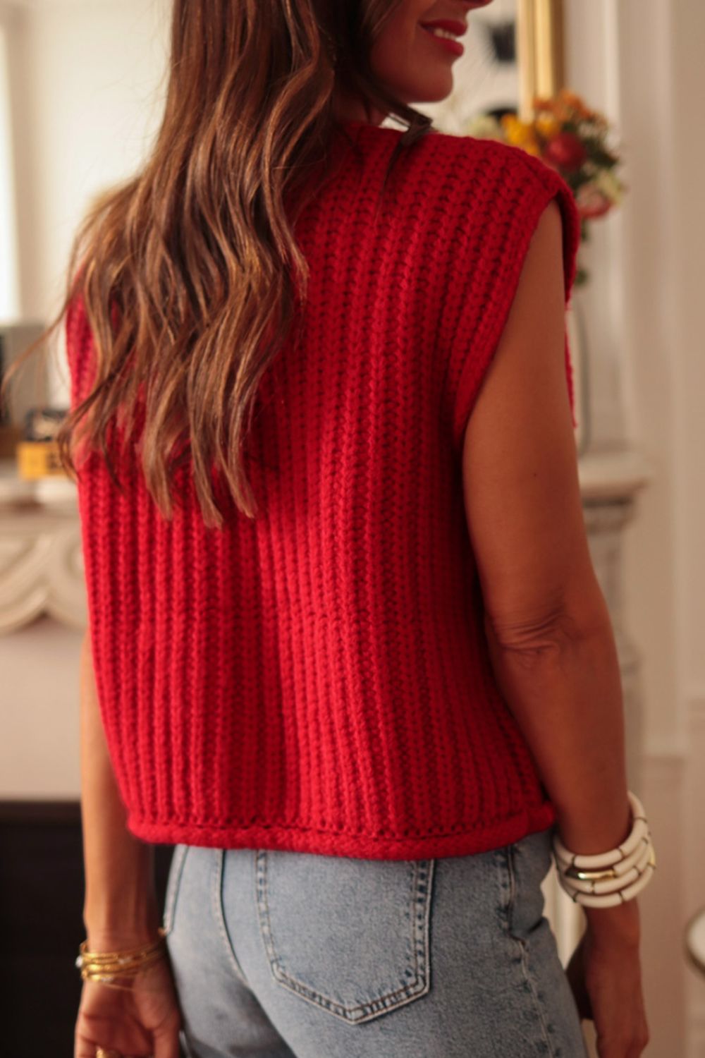 Chunky knit vest in deep red acrylic with ribbed texture and statement buttons, styled casually.