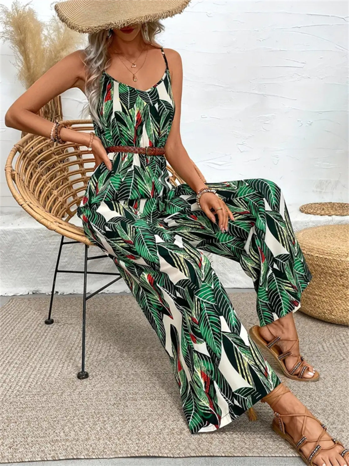 Botanical print cami jumpsuit in dark green with wide legs and a brown belt.