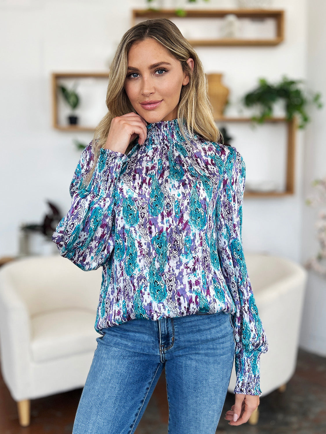 High neck abstract print blouse with smocked cuffs and neckline in blue, purple, and white.