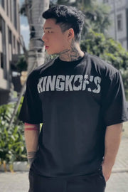 Black oversized graphic tee with distressed "KINGKONG'S" print and crew neck.