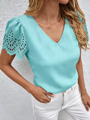 Aqua v-neck blouse with cutout lace detail on short sleeves and puff sleeves.