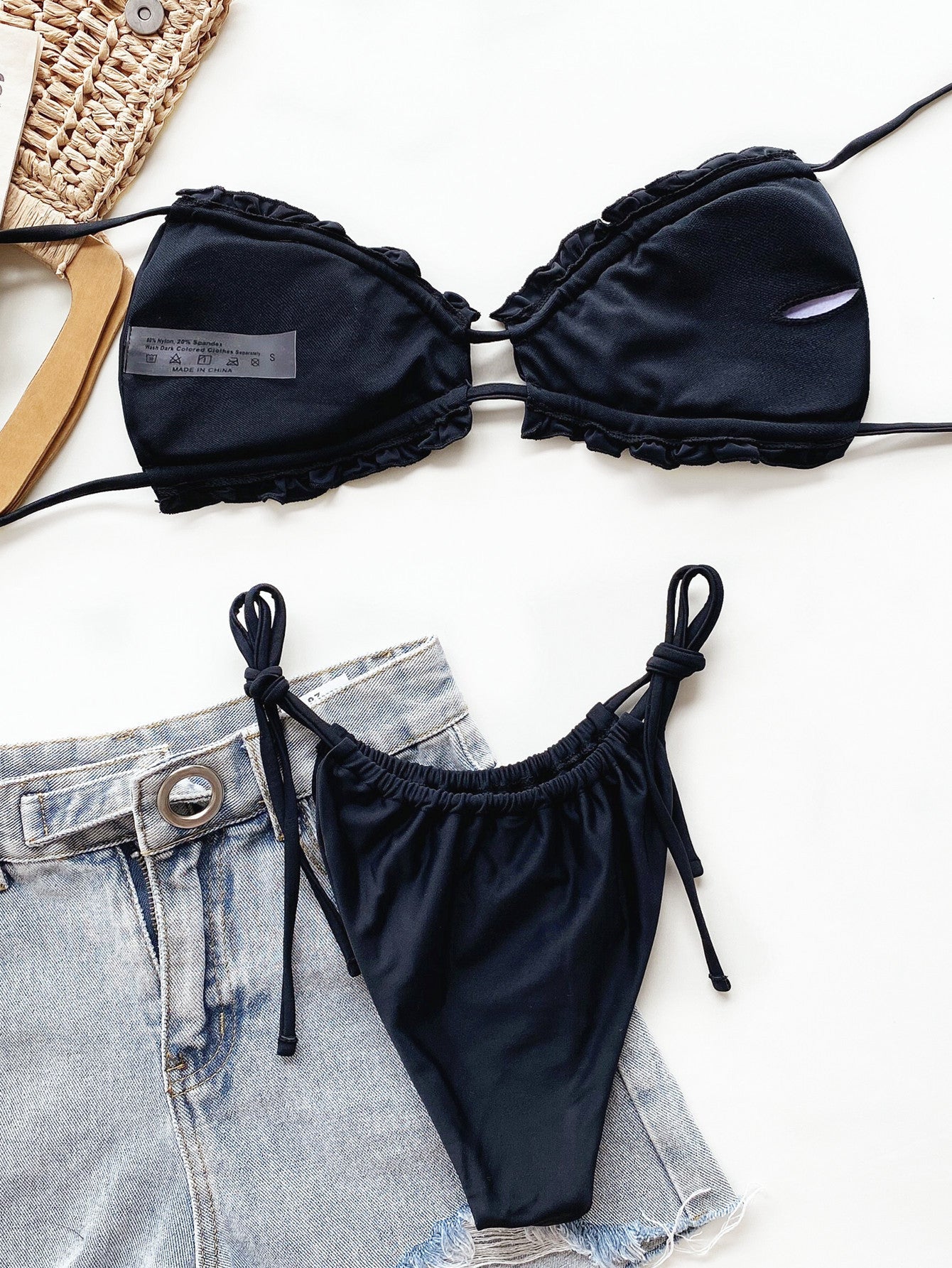 Black ruffle tie bikini set with string bikini bottoms and denim shorts.