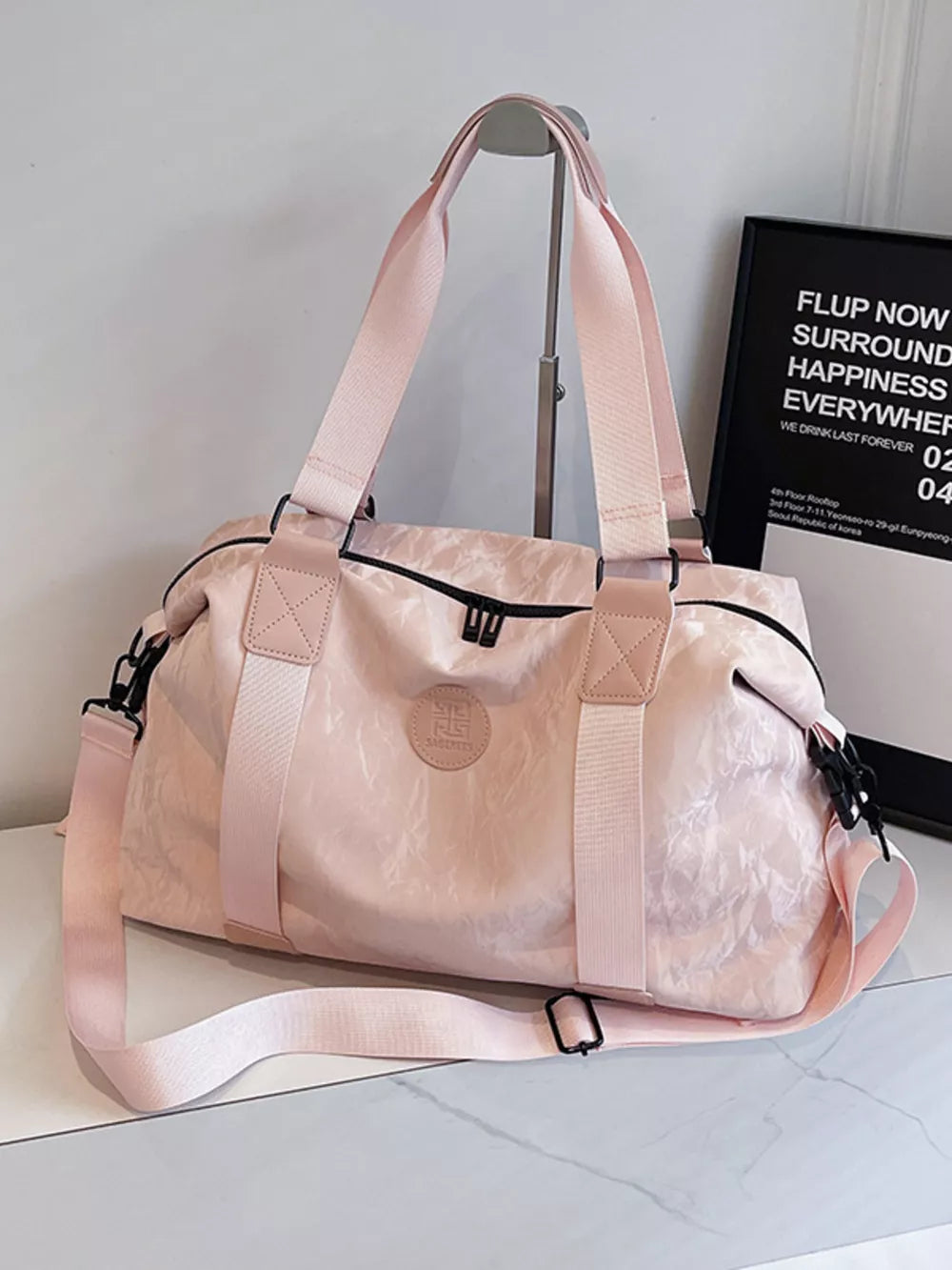 Chic medium blush pink oxford cloth travel bag with floral pattern and adjustable strap.