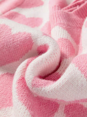 Charming heart pattern knit sweater in blush pink and white acrylic, showing cozy texture.