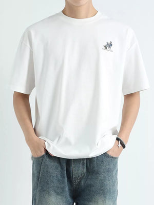 Men's white cotton graphic tee with small chest print and relaxed fit.