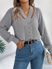 Gray cable knit sweater with cutout neckline and openwork detail.