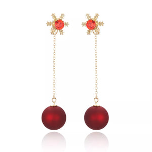 Deep red snowflake drop earrings with gold chain and matte red ball charms.