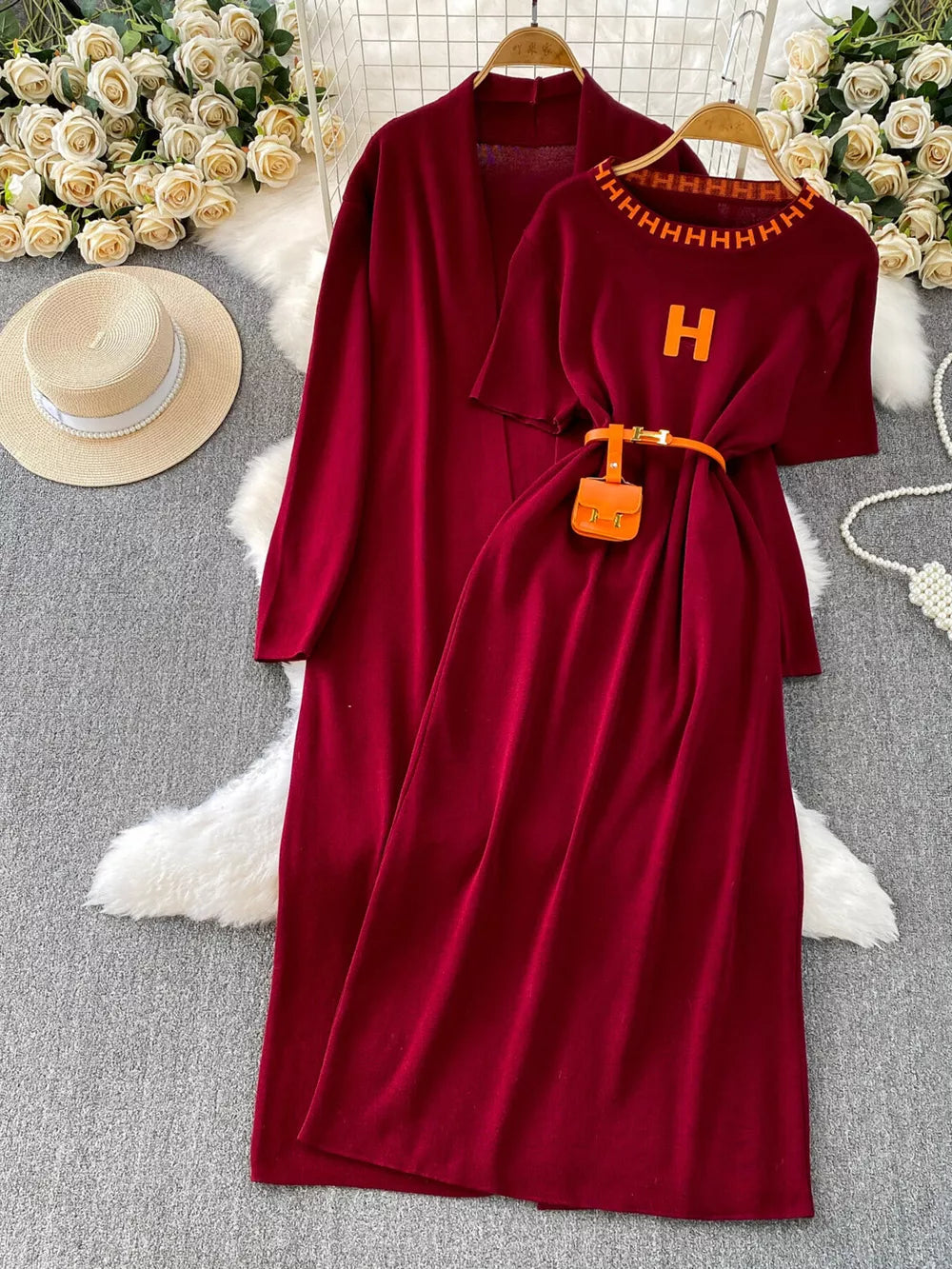 Burgundy knitted maxi dress and matching cardigan with orange belt and mini bag.