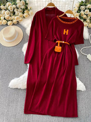 Burgundy knitted maxi dress and matching cardigan with orange belt and mini bag.