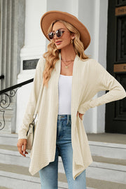 Cream textured knit cardigan with asymmetrical drape front and long sleeves.