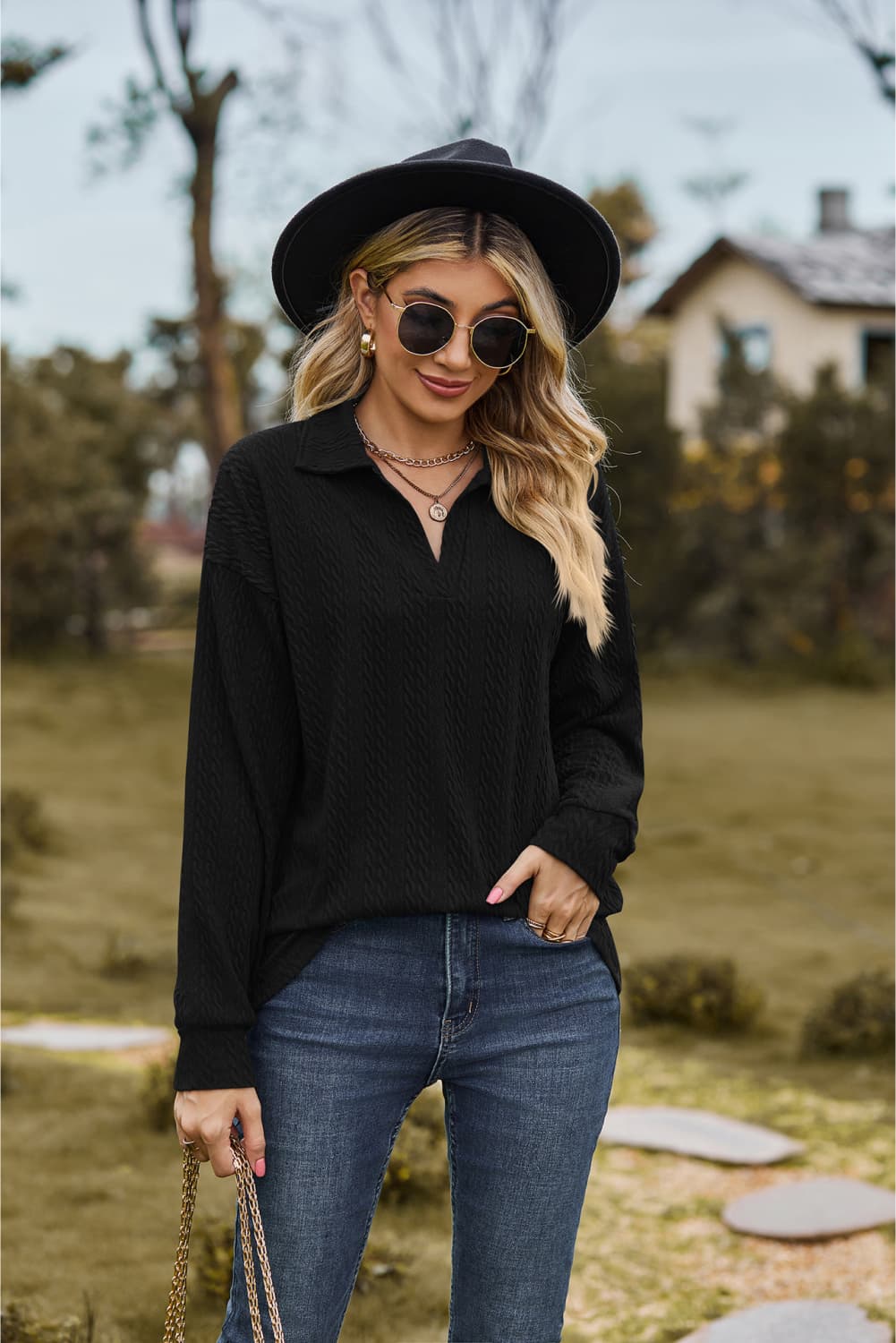 Black textured cable knit polo top with a V-neck and long sleeves.