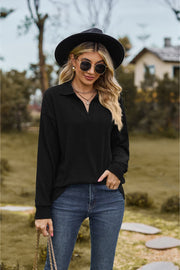 Black textured cable knit polo top with a V-neck and long sleeves.