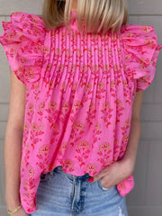 Pink floral print blouse with ruffled flutter sleeves and smocked bodice.