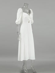 White midi dress with sweetheart neckline, puff sleeves, cutout detail and twisted front.