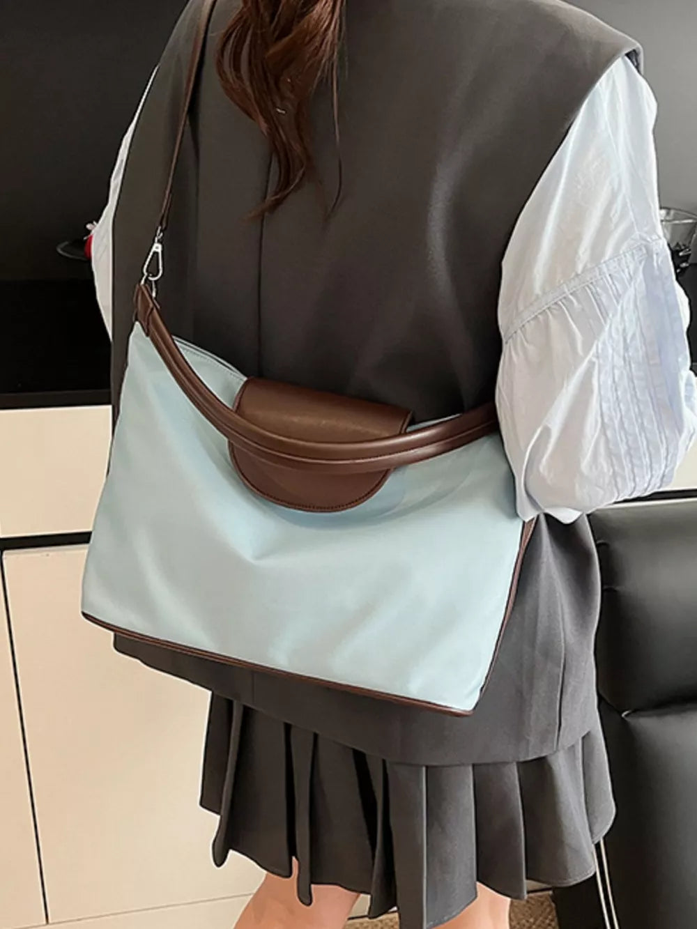 Chic canvas hobo crossbody bag in blue with brown trim and handle detail.