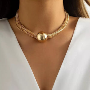 Choker necklace with layered gold chains and a large spherical pendant.