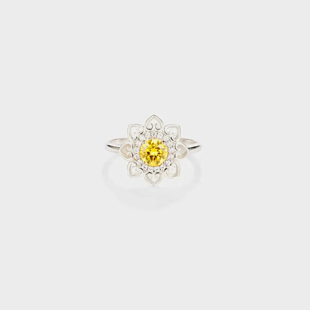 Silver ring with yellow center stone and floral filigree design.