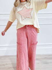 Cream t-shirt with pink striped star graphic and stud details, paired with pink wide-leg cargo pants.