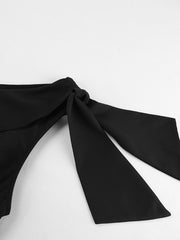 Black asymmetrical mini dress with a bow detail on the shoulder.