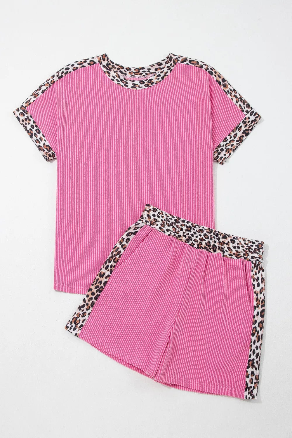 Pink ribbed pajama set with crew neck top and shorts, featuring leopard trim detail.