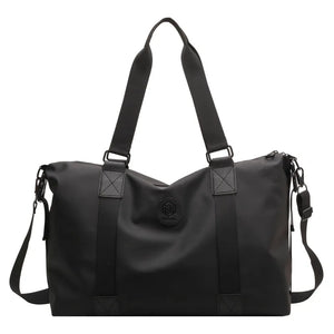 Black canvas duffel bag with dual handles, adjustable shoulder strap, and embossed logo detail.