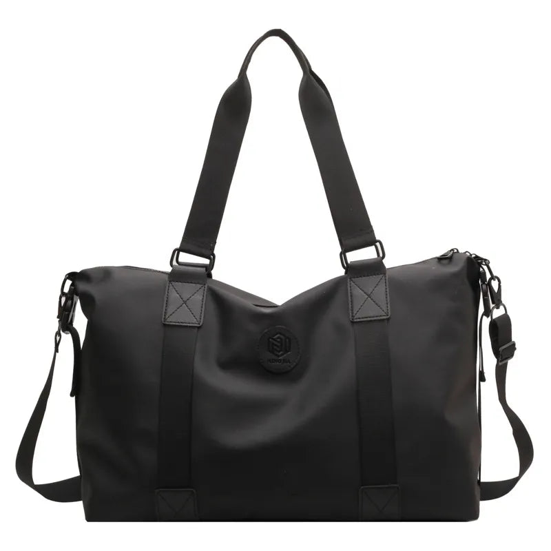 Black canvas duffel bag with dual handles, adjustable shoulder strap, and embossed logo detail.