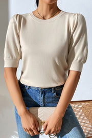 Cream knit sweater with puff sleeves and crew neck, styled with jeans and a clutch.