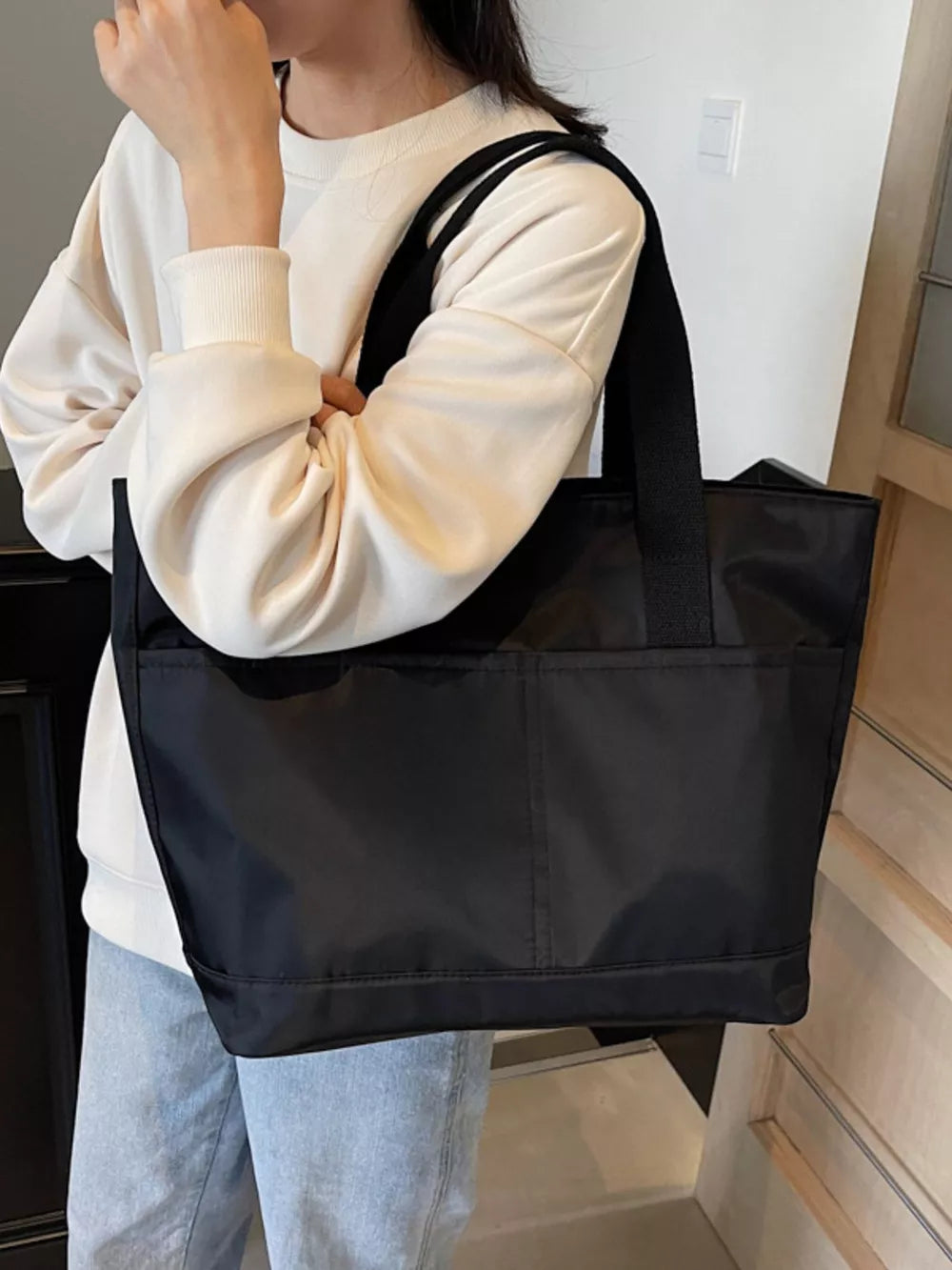 Black Oxford cloth shoulder tote bag with exterior pockets and black straps.