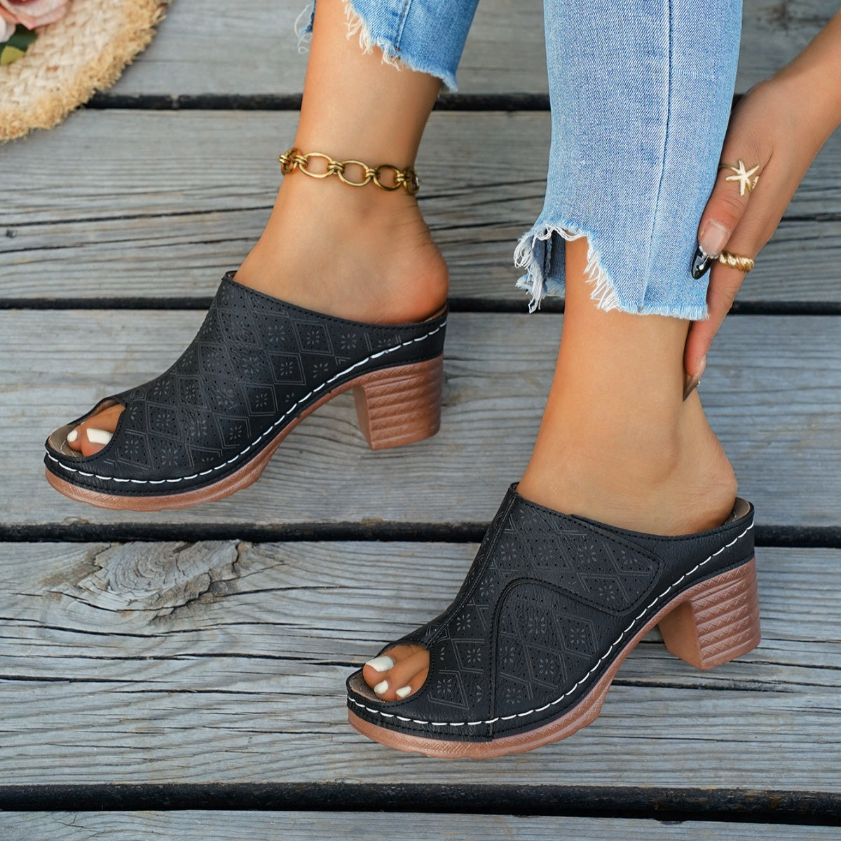 Black peep-toe mules with perforated diamond pattern and block heel.