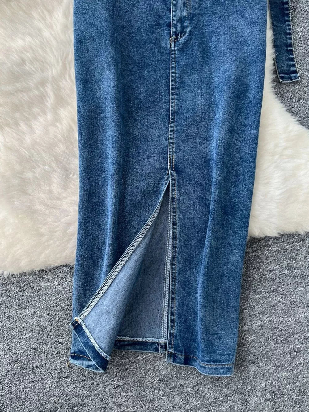 Blue denim maxi skirt with high slit and visible stitching detail