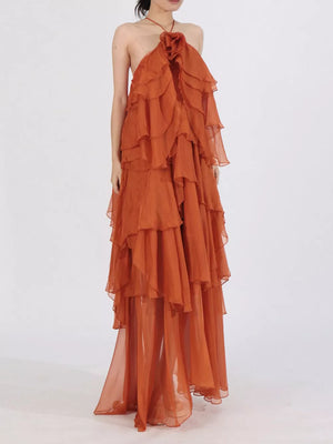 Orange ruffle halter maxi dress with floral detail and flowing tiered skirt.