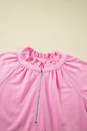 Pink cotton zip-up top with ruffled neckline and gathered shoulders