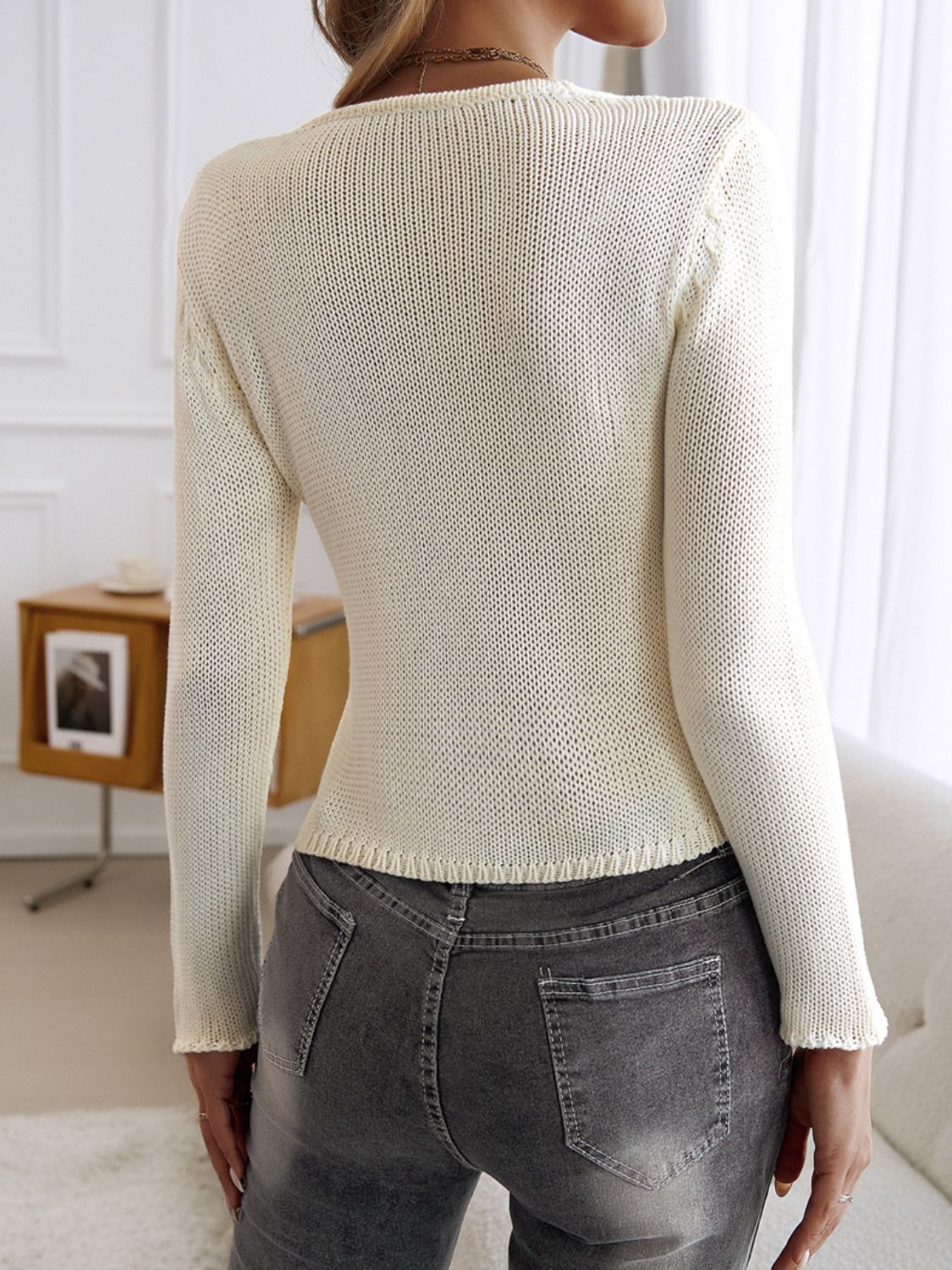 White knit cropped cardigan with long sleeves and a textured knit detail on the shoulders.