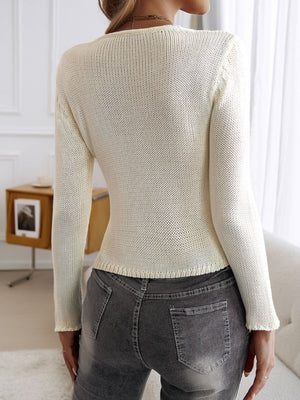 White knit cropped cardigan with long sleeves and a textured knit detail on the shoulders.