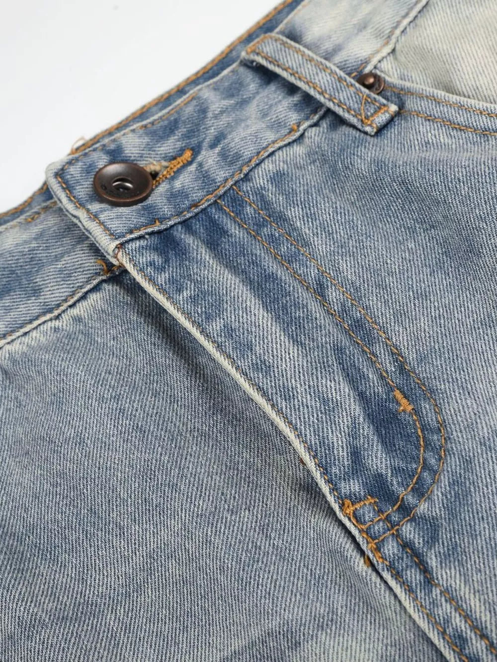 Men's vintage wash wide leg jeans in light blue denim, close-up of button fly and stitching.