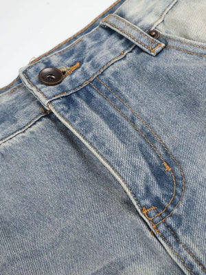 Men's vintage wash wide leg jeans in light blue denim, close-up of button fly and stitching.