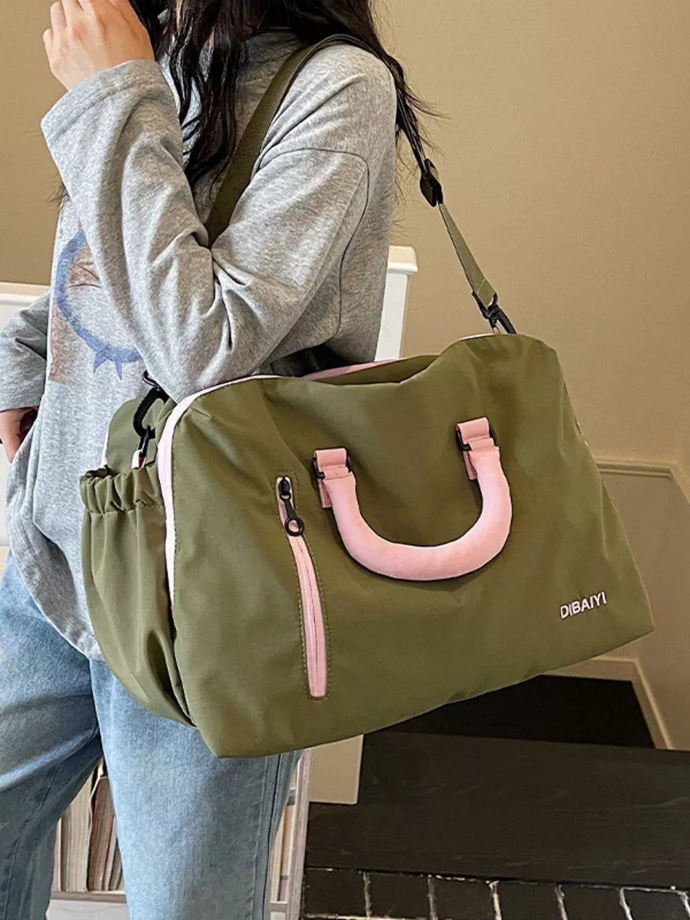 Chic olive travel bag with pink accents and adjustable strap.