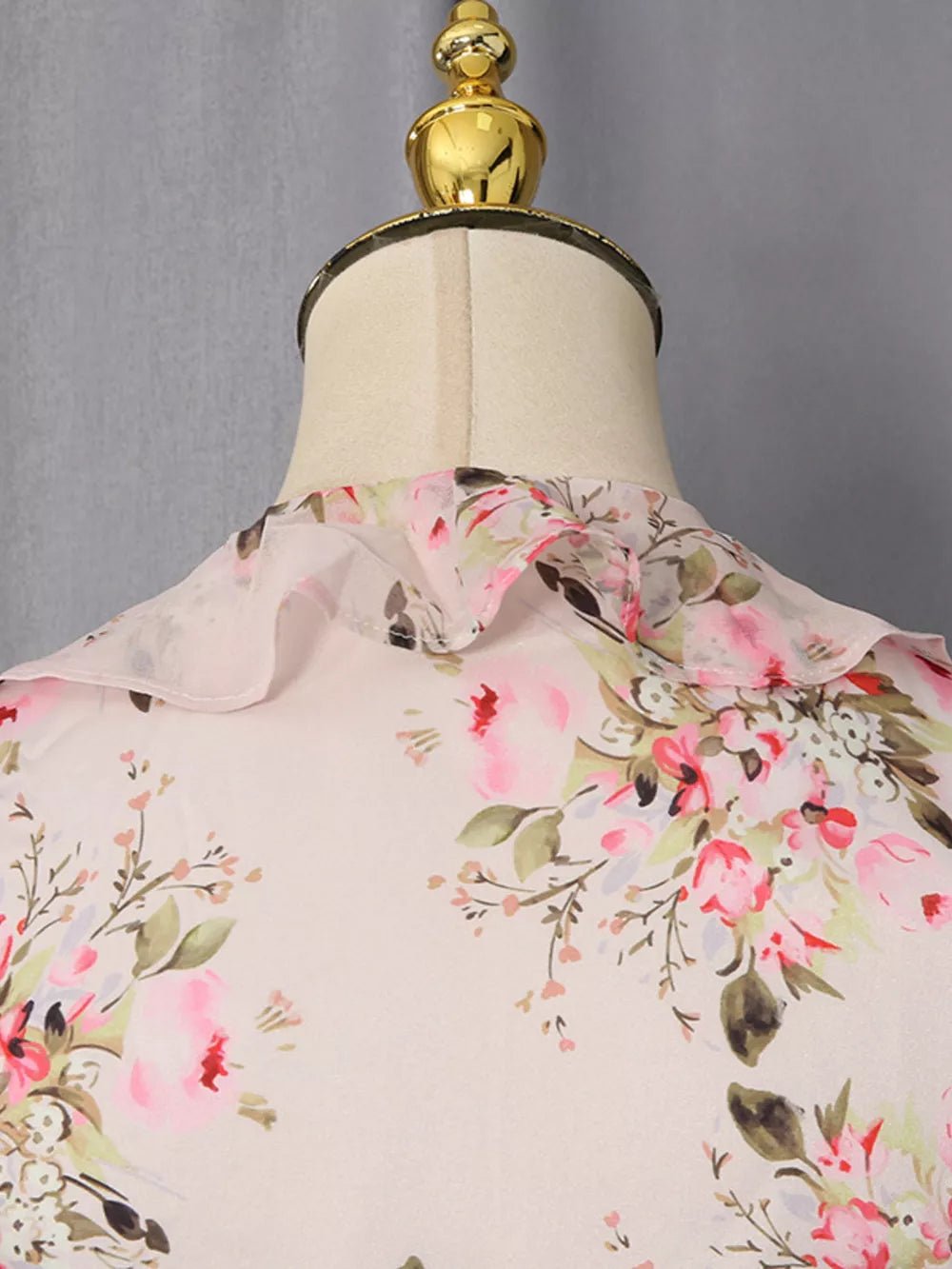 Charming ruffled floral mini dress with pink and green blossoms on a light background.