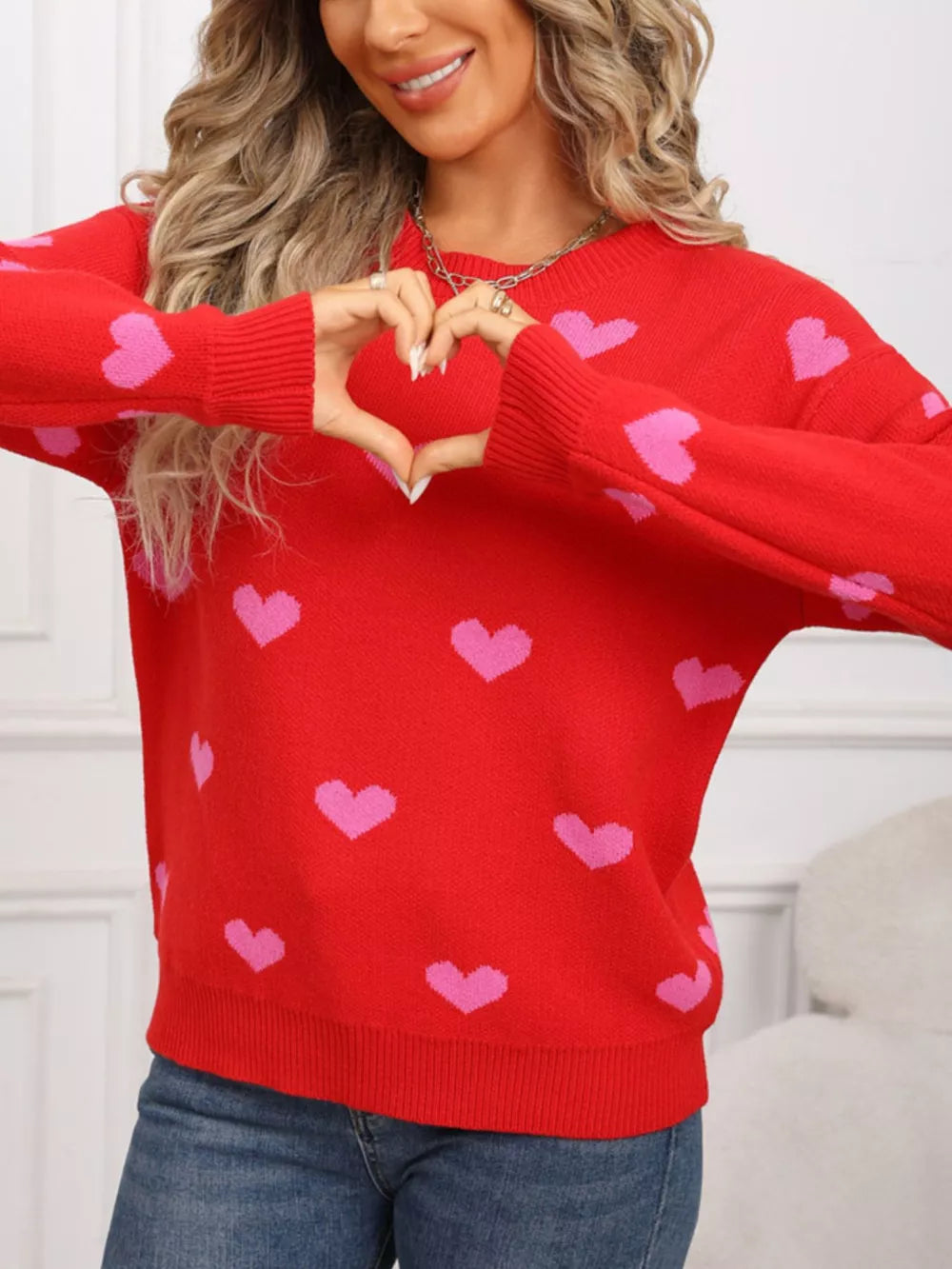 Cozy red acrylic knit sweater with pink heart print, crew neck, and long sleeves.