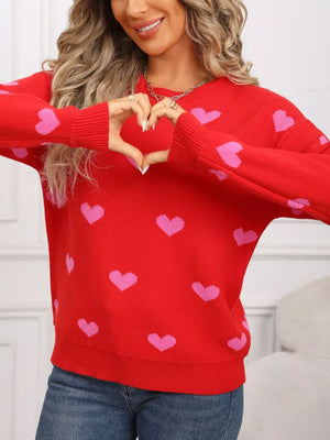 Cozy red acrylic knit sweater with pink heart print, crew neck, and long sleeves.