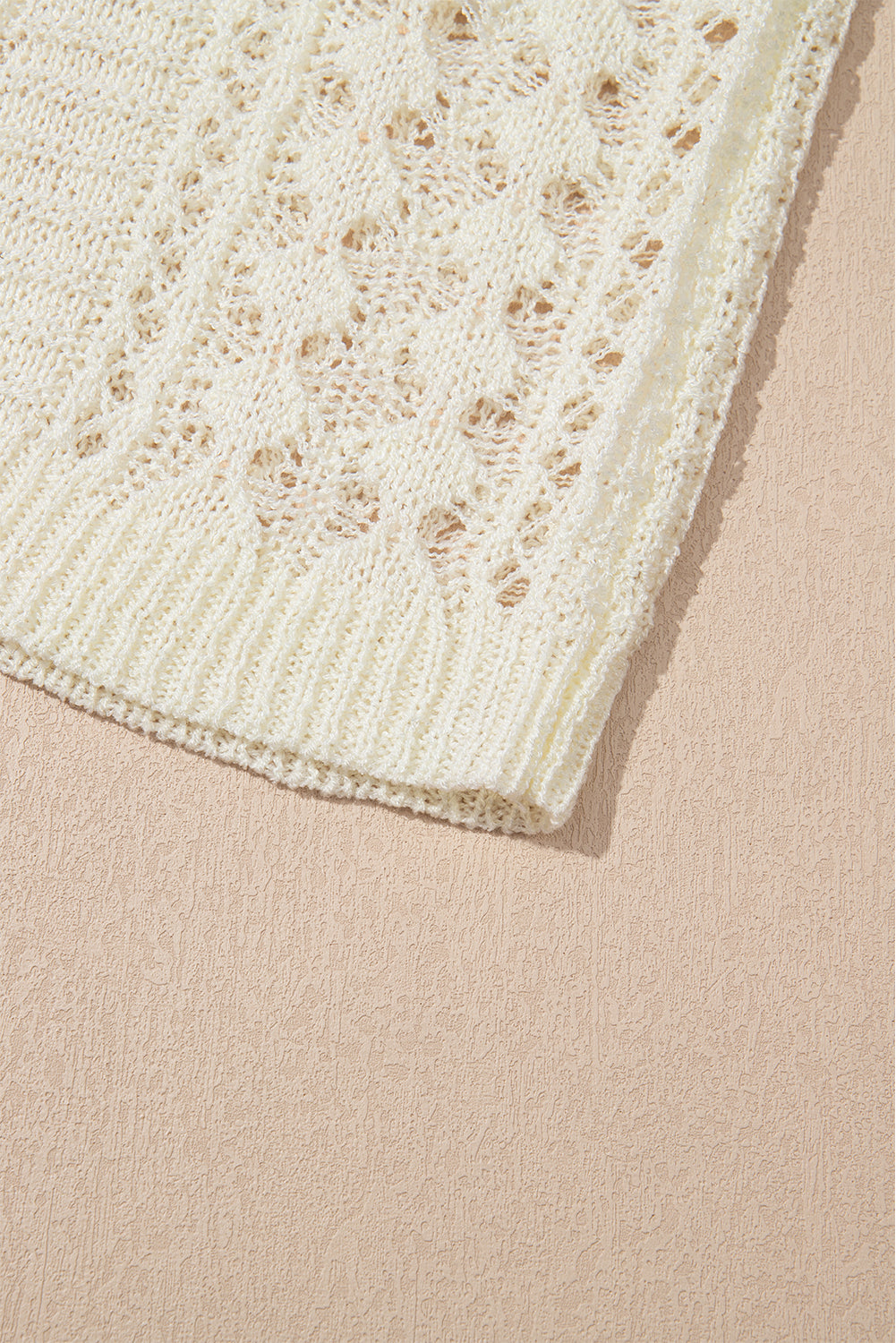 Beige openwork knit beach cover-up with a textured pattern and ribbed hem.
