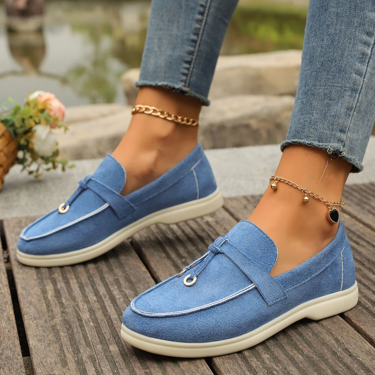 Blue decorative strap flat slip-ons with white piping and gold hardware detail.