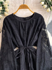 Black embroidered tie-waist dress with sheer floral sleeves and round neckline.