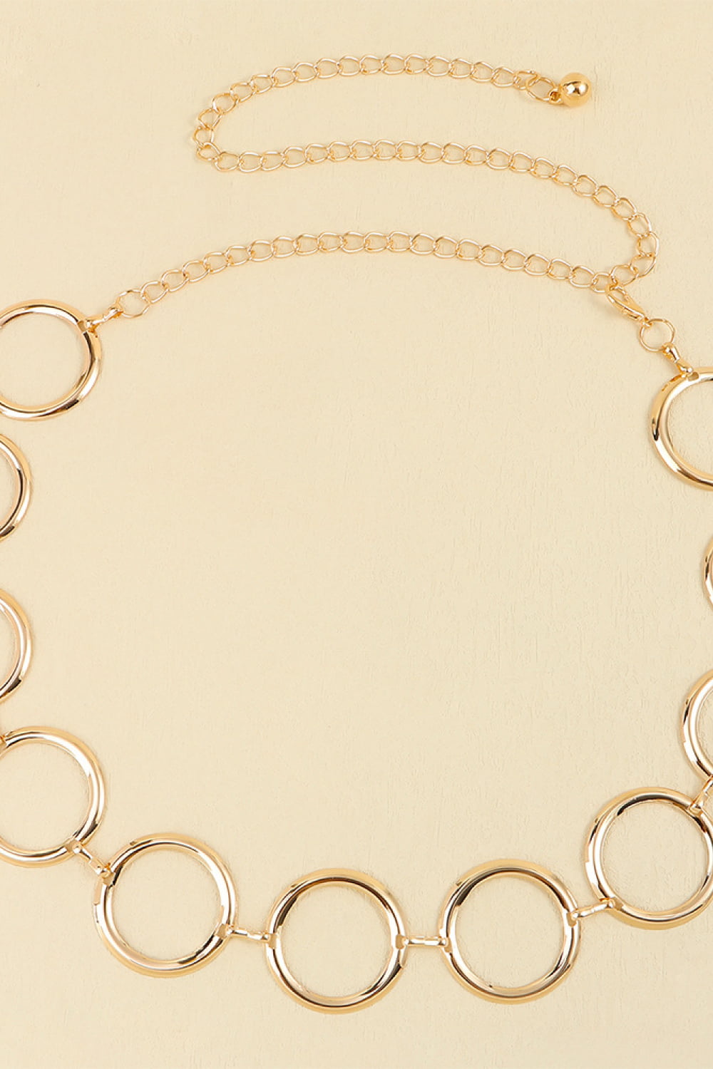 Gold geometric circle waist chain with a delicate link chain and clasp closure.