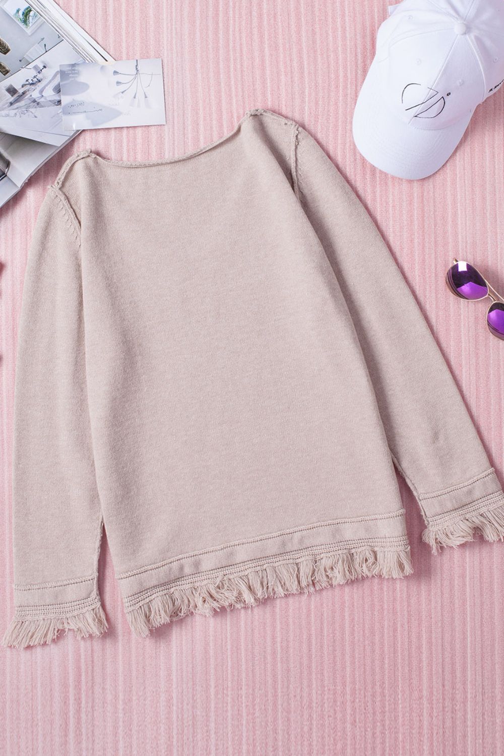 Eggshell knit sweater with off-the-shoulder neckline and fringe trim detail.