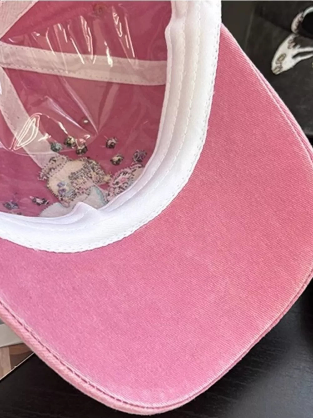 Pink cotton baseball cap with embroidered detail and clear plastic lining.