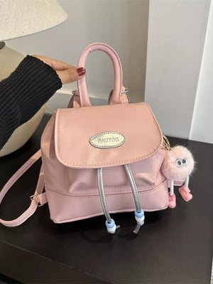 Pink mini leather drawstring backpack with cute fuzzy charm and beaded pull cords.
